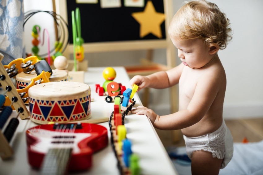 Ein Baby mit Windel spielt mit Holzspielzeug