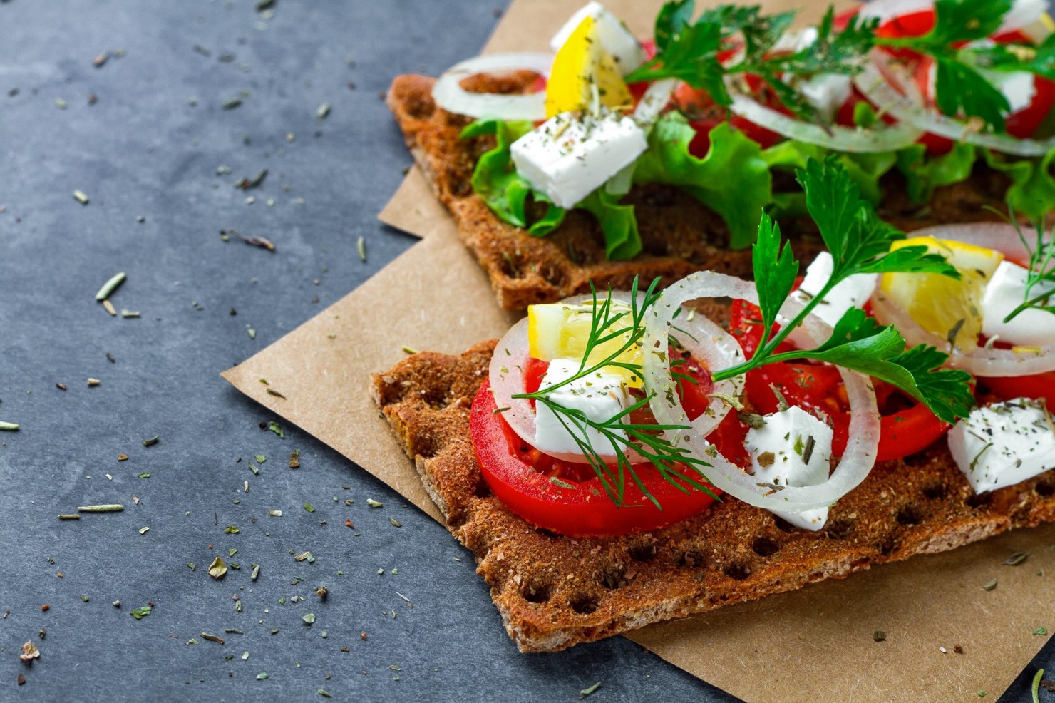 Knäckbrot mit Tomate, Feta, Zwiebel auf Steinplatte
