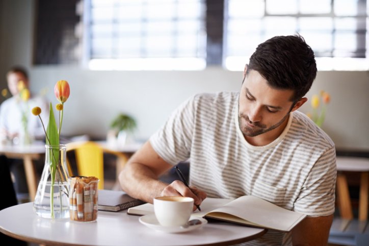 Ein Mann führt ein Dankbarkeitsjournal in einem Café
