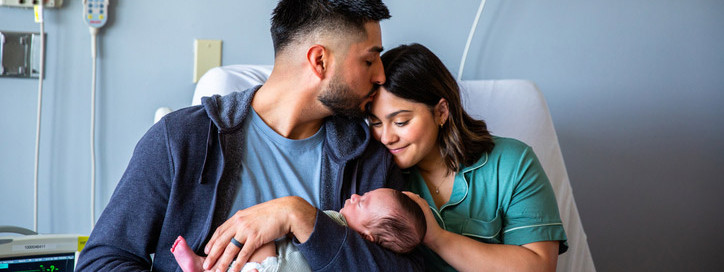 Frisch gebackene Eltern halten ihr Neugeborenes im Arm