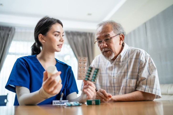 Eine Pflegekraft erklärt einem Senior, welche Medikamente Wechselwirkungen hervorrufen