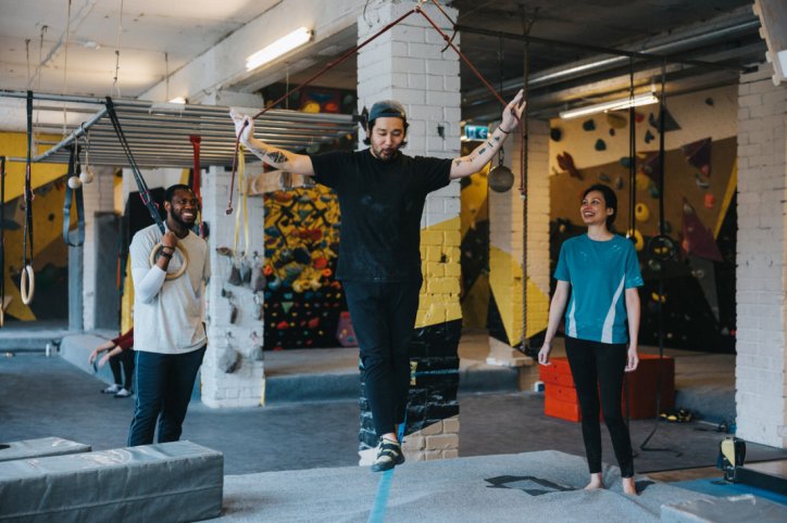 Eine sportliche Gruppe macht Slackline in einer Boulderhalle.