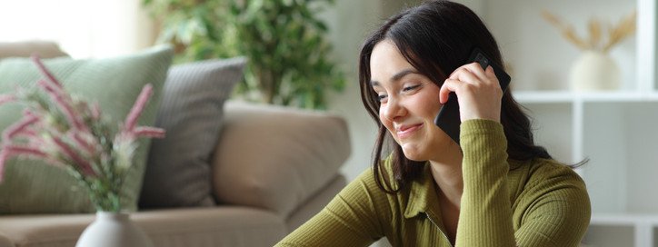 Eine junge Frau telefoniert und schmunzelt dabei.