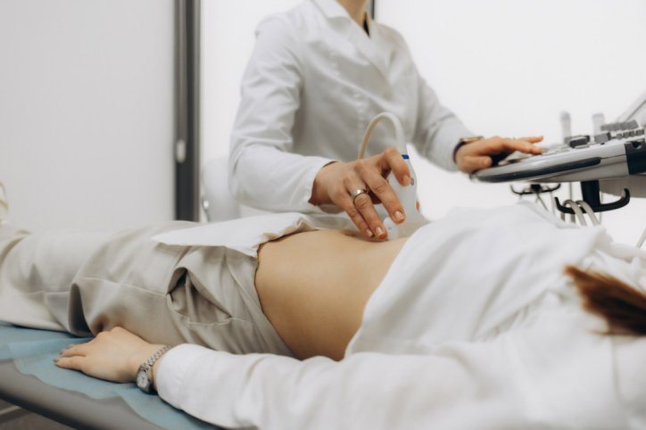 Eine Frau wird von einer Ärztin am Bauch mit Ultraschall untersucht.