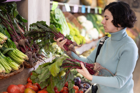 Eine Frau kauft Knollen- und Wurzelgemüse im Supermarkt ein