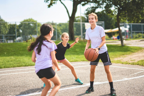 Drei Mädchen spielen gemeinsam Basketball. Sie haben Freude an der sportlichen Bewegung.