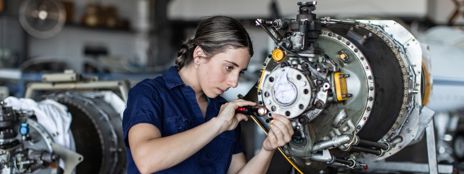 Eine junge Frau repariert eine Maschine in einer Werkstatt.