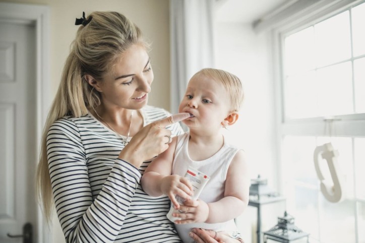Eine Mutter wendet Zahnungsgel bei ihrem Kleinkind an