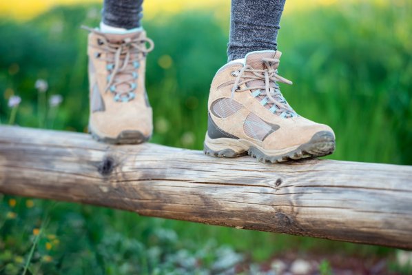 Nahansicht, wie jemand mit Wanderschuhen auf einem Balancierbalken läuft