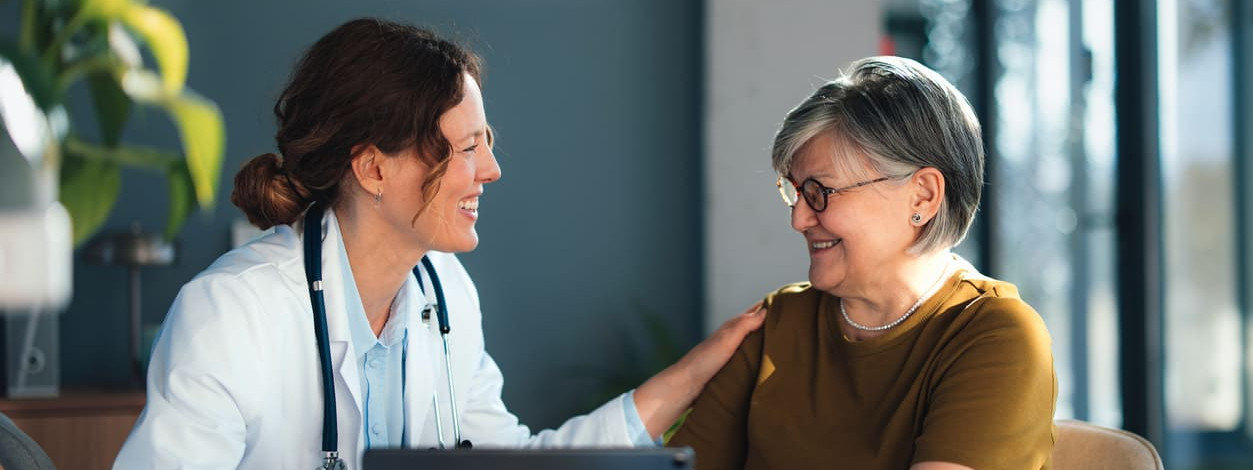 Freundliche Ärztin spricht zu älterer Patientin