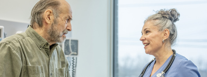 Ein etwa 70-jähriger Mann wir von einer Ärztin in der Praxis zu seiner Gesundheit beraten.