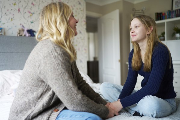 Reife Mutter, Die Mit Teenager-Tochter Zu Hause Auf Dem Bett Sitzt