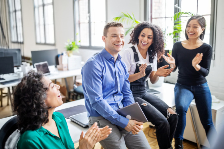 Beschäftigte applaudieren ihrem Kollegen.