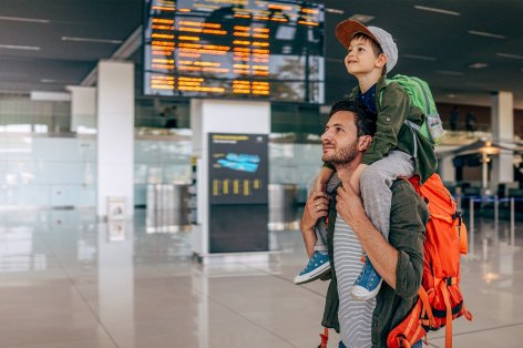 Vater mit Sohn auf den Schultern im Flughafen.