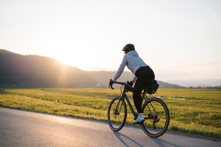 Eine Person fährt an einem Feld entlang mit dem Rad.