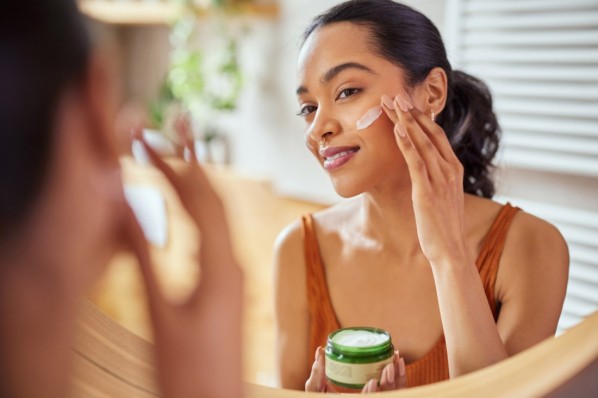 Eine Frau wendet nach dem Dermaplaning Feuchtigkeitscreme an
