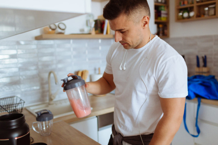 Ein junger Mann mischt Eiweißshake mit Aminosäuren an