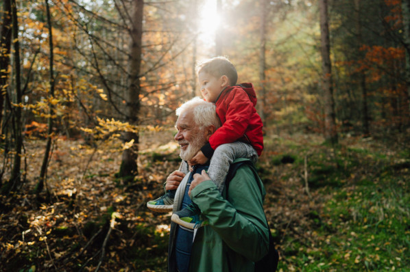 Photo of grandfather and his grandson having a walk through the forest