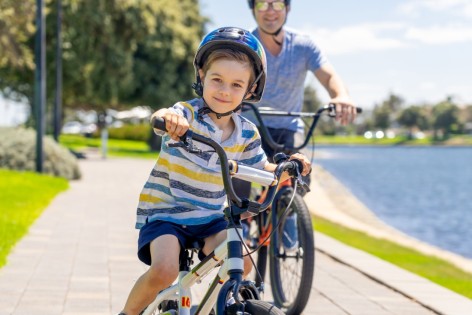 Ein Vater bringt seinem etwa 6 jährigen Sohn das Fahrradfahren bei.