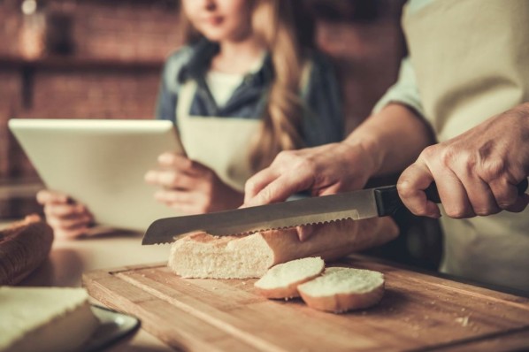 Vater und Tochter schneiden Brot klein.