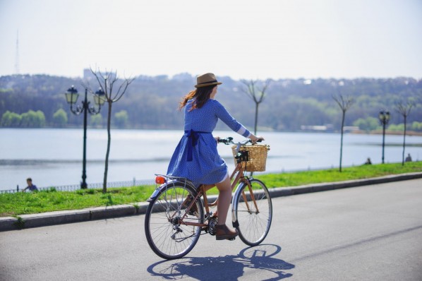 Eine junge Frau fährt mit Ihrem Fahrrad an eine Uferpromenade entlang.