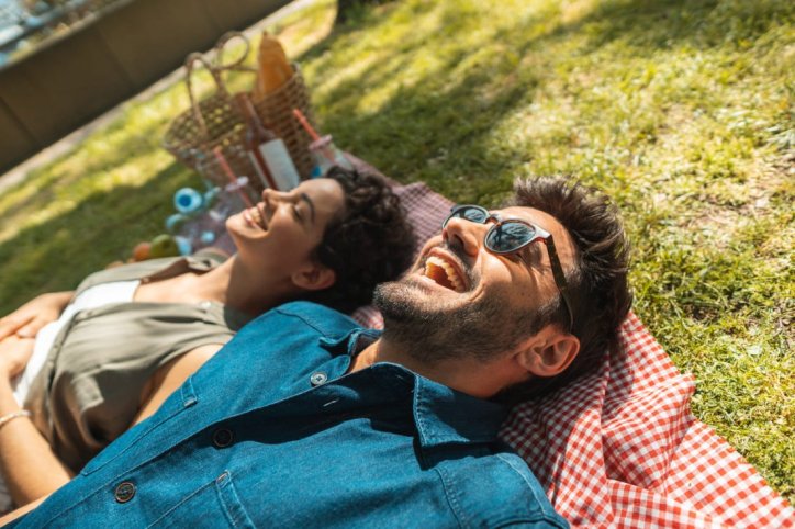 Ein gut gelauntes Paar entspannt nebeneinander auf einer Picnicdecke