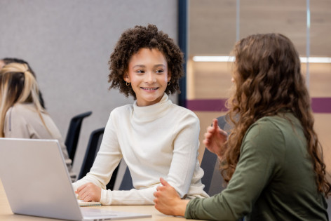 Ein Mädchen, was gegen Meningokokken ACWY geimpft ist, spricht mit einer anderen Jugendlichen.