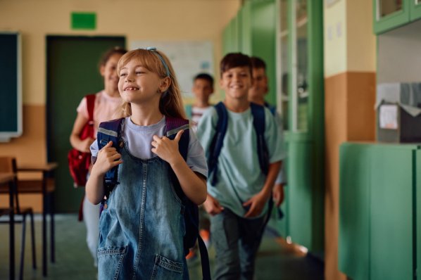 Lächelndes Mädchen geht mit Klassenkameraden in Klassenraum