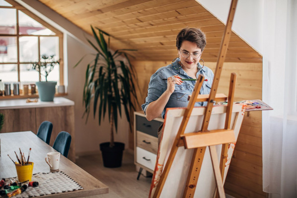 Eine Künstlerin malt an einem Stativ ein Bild.