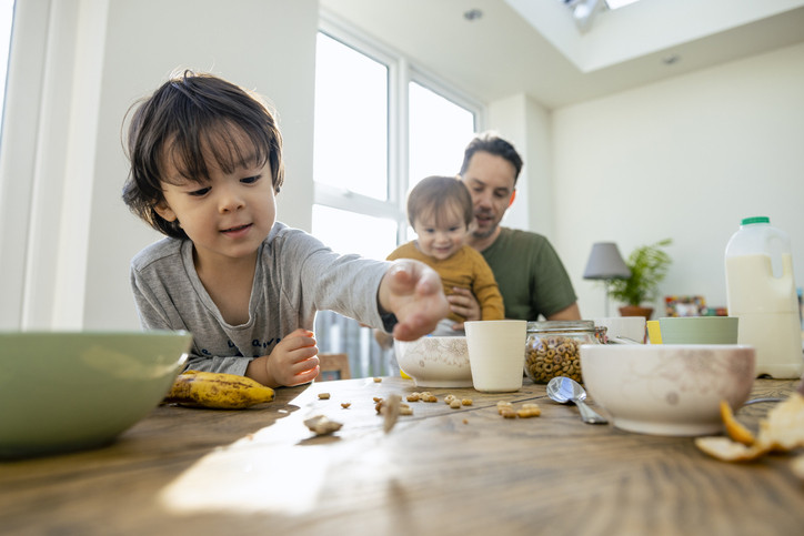 Zwei Kinder und ihr Vater essen gemeinsam entspannt am Esstisch.