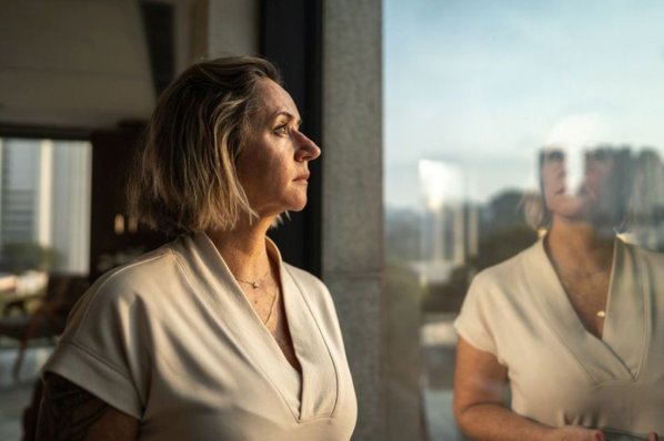 Eine Frau schaut nachdenklich oder besorgt aus dem Fenster.