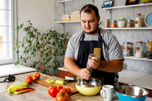 Junger Mann bereitet sich einen leckeren Salat in der heimischen Küche zu.