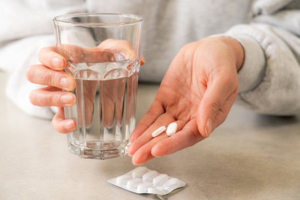 Junge Frau hält Tabletten in der Hand. 