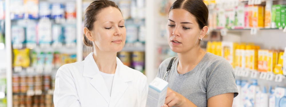 Eine Frau wird von einer Apothekerin zu einem Arzneimittel beraten.