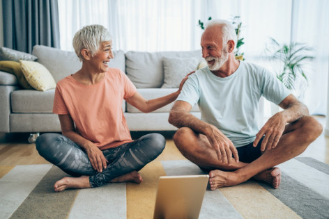 Ein älteres Paar macht zu Hause gemeinsam Yoga.