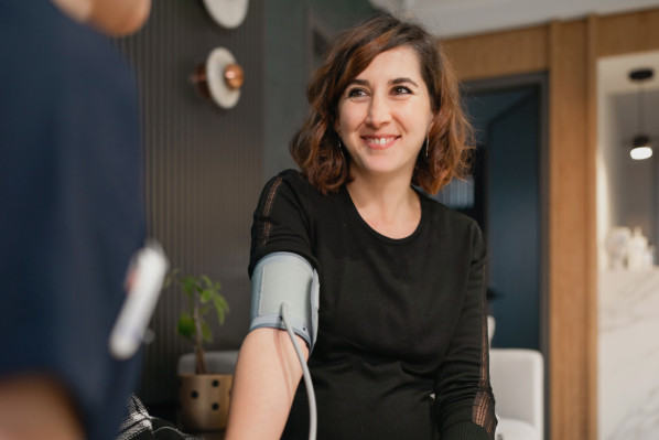 junge Frau beim Blutdruck messen beim Arzt