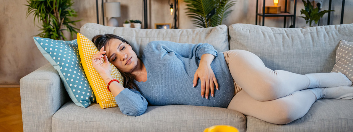 Eine schwangere Frau schläft auf dem Sofa