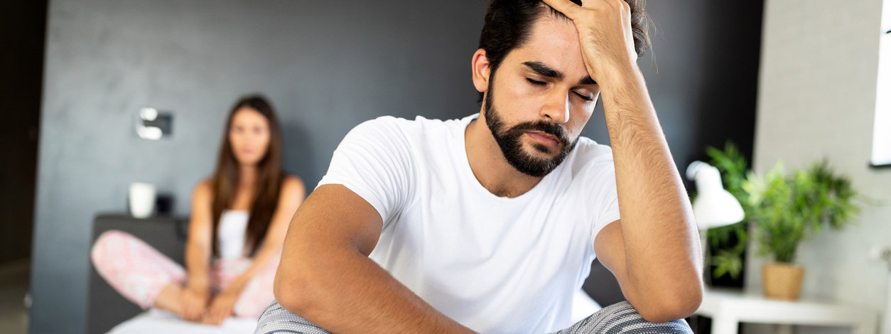 Ein Mann sitzt nach einer Erektionsstörung bedrückt auf der Bettkante