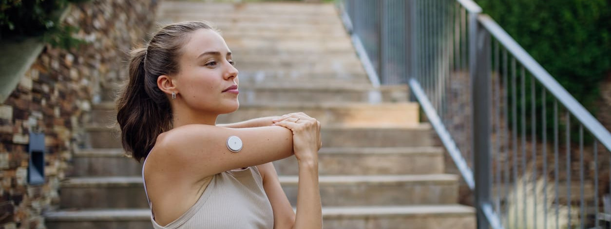 Junge Diabetikerin macht Dehnübungen vor einer AußentreppeJunge Diabetikerin macht Dehnübungen vor einer Außentreppe