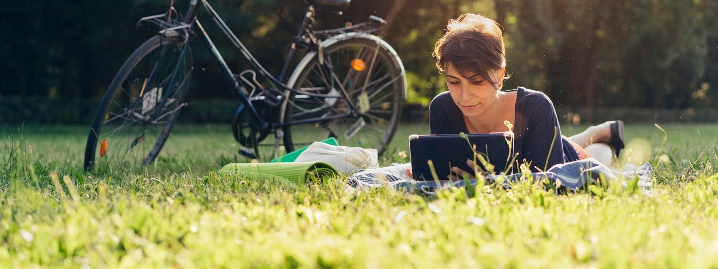 Frau liegt neben ihrem Fahrrad auf einer Sommerwiese