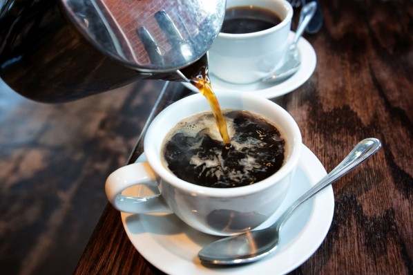 Kaffee wird in eine weiße Porzellantasse gegossen.