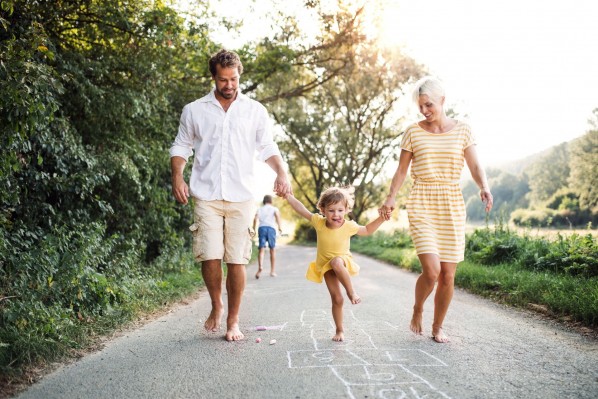 Eine kleine Familie läuft barfuß einen asphaltierten Weg entlang.