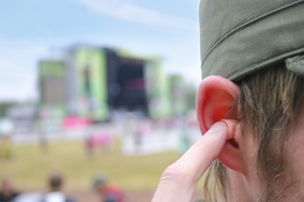 Ein junger Mann, der auf einem Musikfestival Ohrstöpsel benutzt.