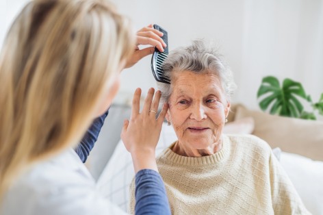 Pflegerin kämmt Seniorin die Haare