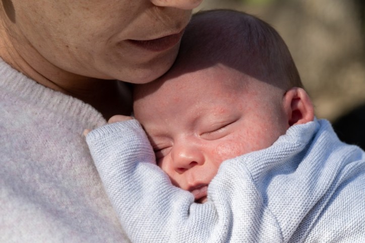 Eine Mutter hält ihr Baby mit Neugeborenenakne.