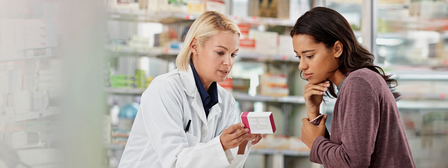 Eine Frau wird in der Apotheke von der Apothekerin zu einem Arzneimittel beraten.