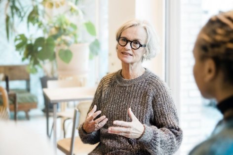 Eine etwa 60 jährige Frau sitzt bei einer Therapiegruppe und redet. Dabei gestikuliert sie.
