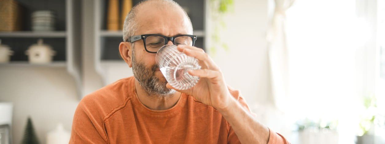 Ein Mann genießt ein Glas Wasser mit Kohlensäure
