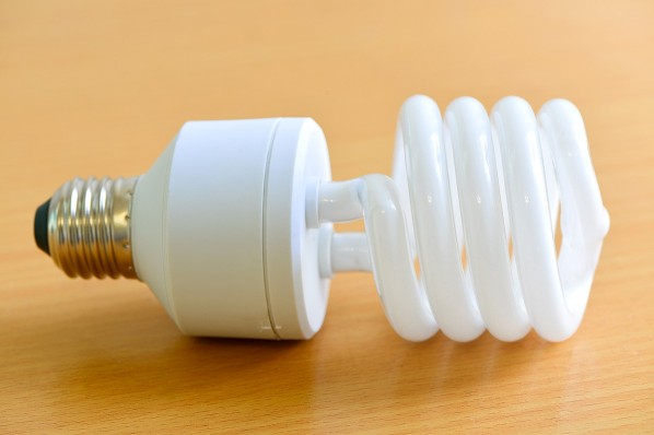 Eine gewundene Energiesparlampe liegt auf einem Parkettboden.