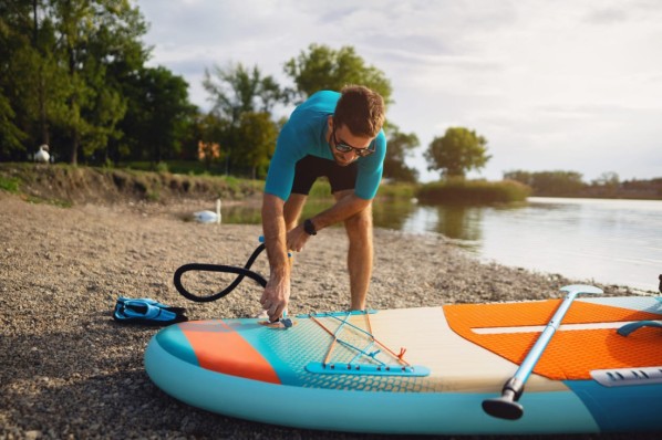 Ein Mann füllt sein aufblasbares SUP-Board mit Luft.